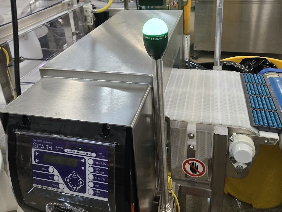 Fortress Stealth metal detector with a green status lamp on a running production line